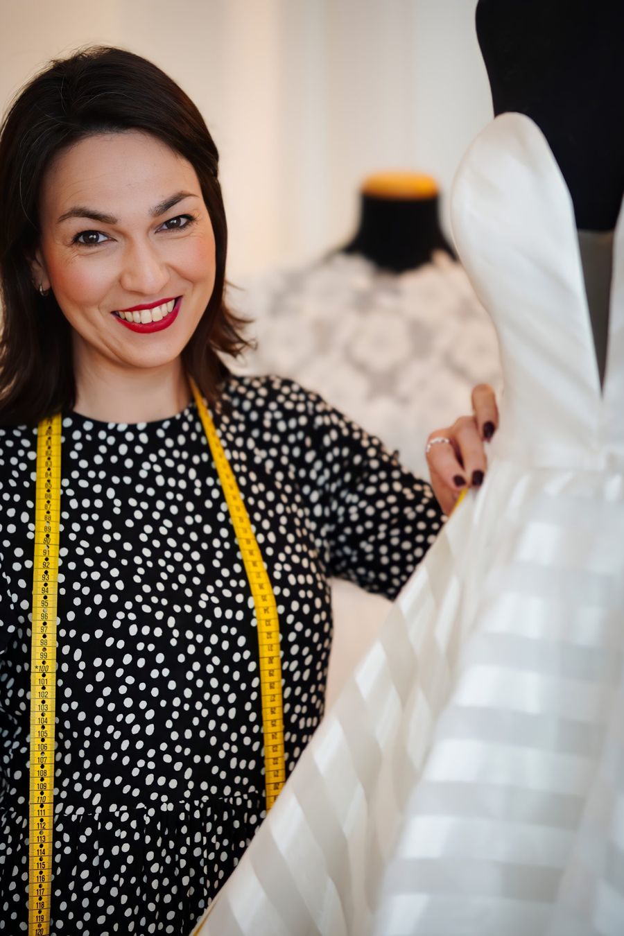 Simone als Schneiderin Simone mit Maßband um ihren Hals beim ändern eines Brautkleides
