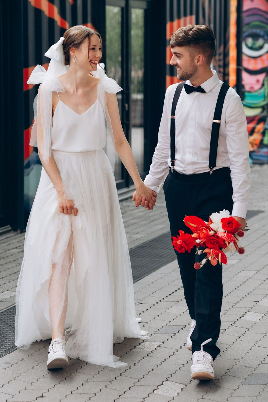 junges Brautpaar im Werksviertel junge Braut im Zweiteiler mit Top mit Schleifen und Softtüllrock