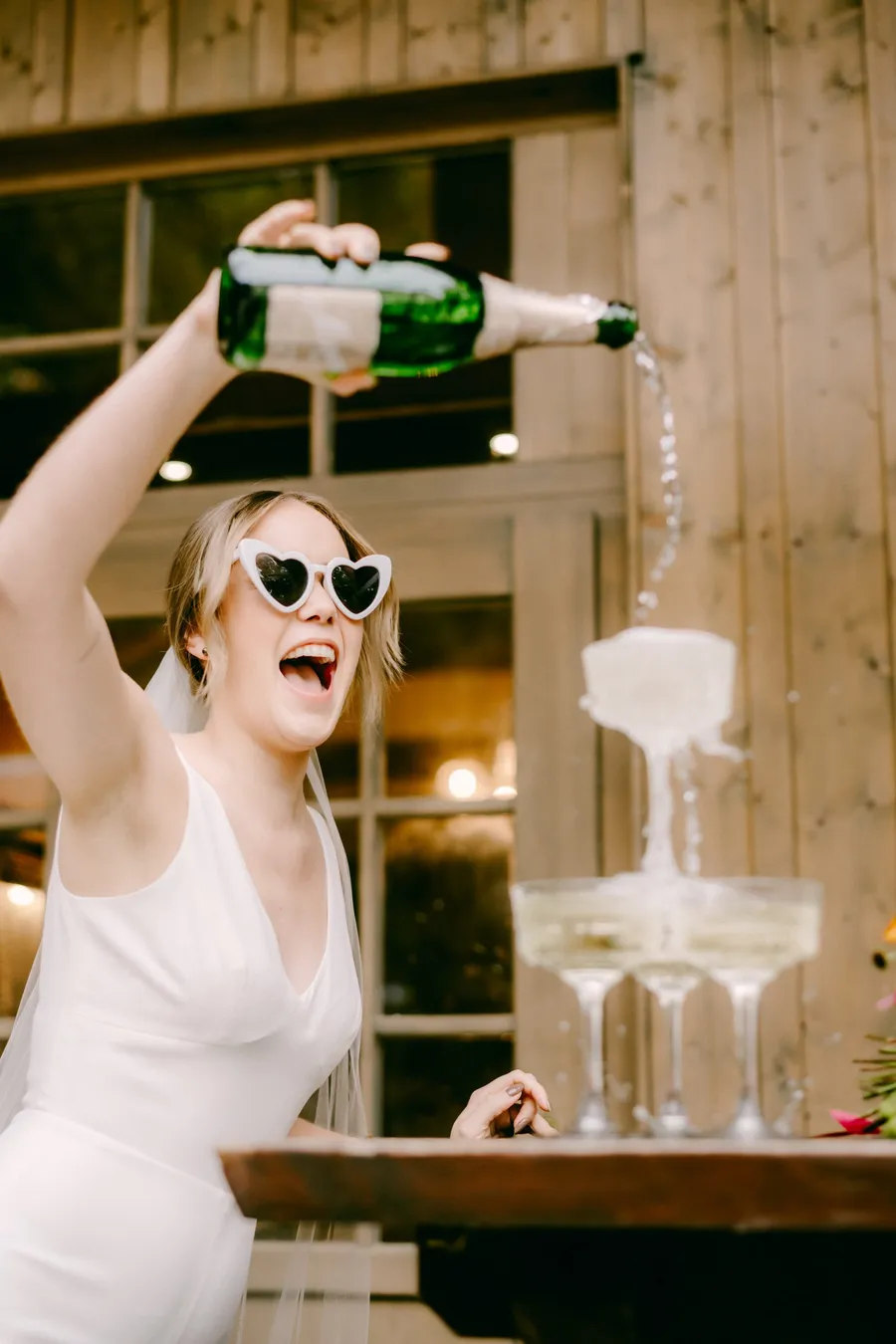 Braut im Jumpsuit schenkt sich ein Glas Champagner ein