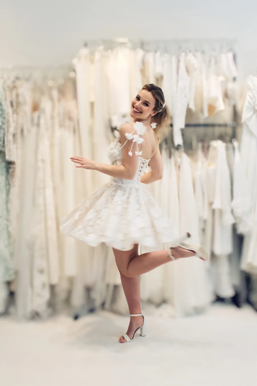 tanzende Braut in kurzem Brautkleid mit 3d Blüten an der Schulter